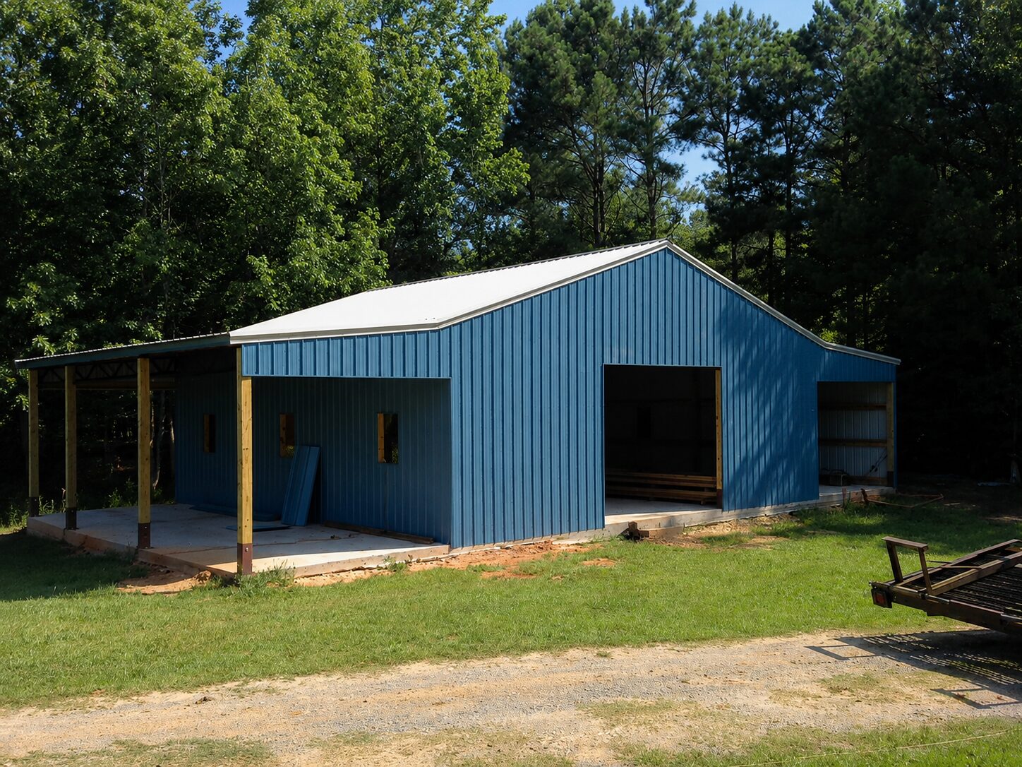 Blue pole barn with open lean-to and covered work bay