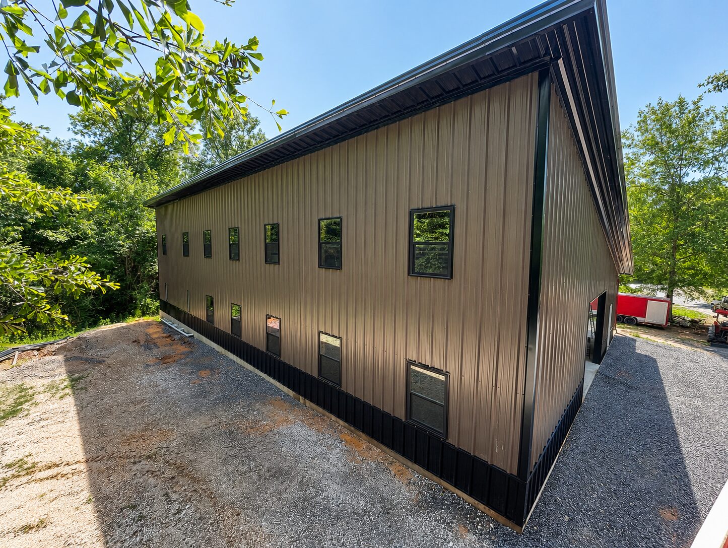 Two-story buckskin barndominium with black wainscot and dark trim